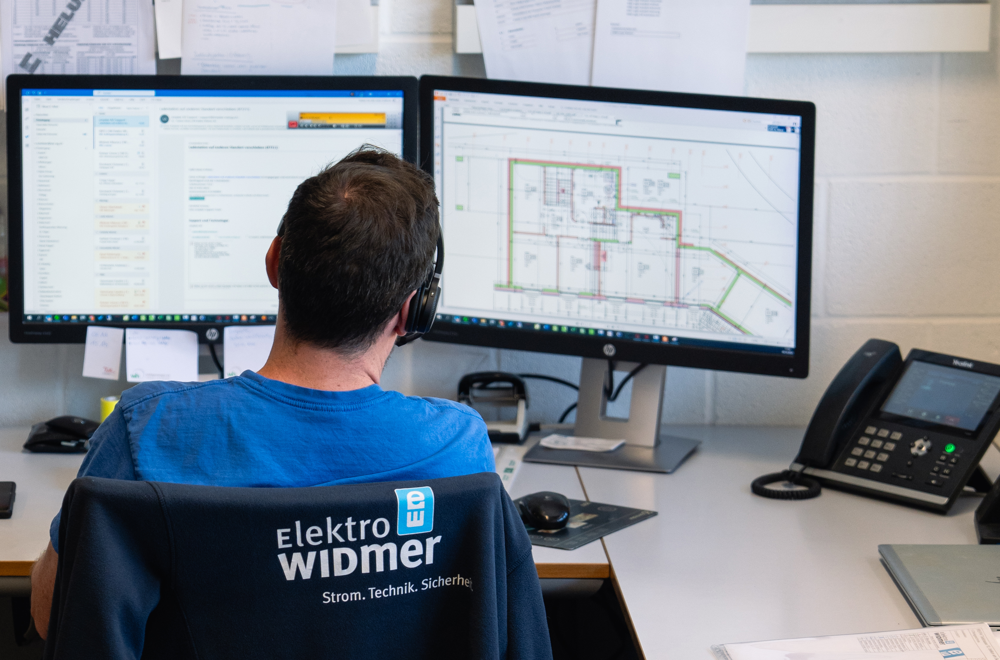 Mitarbeiter der Elektroplanung sitzt am Tisch mit zwei Bildschirmen mit Schema